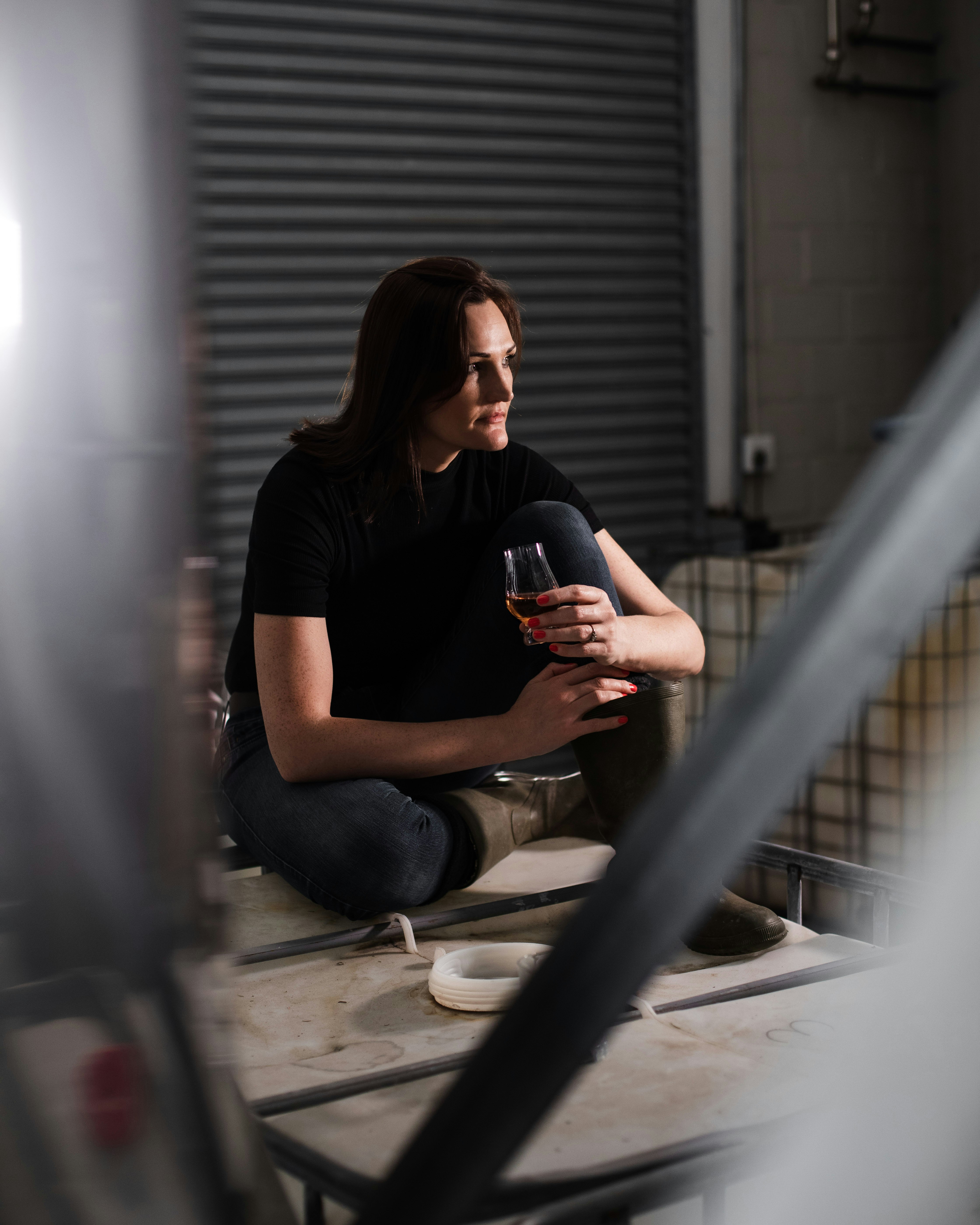 woman in black crew neck t-shirt and blue denim jeans sitting on white concrete floor